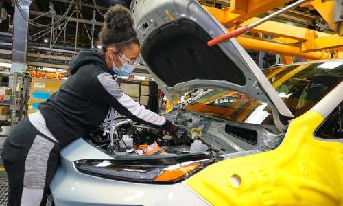 UAW Local 5960 member Kinethia Black fills the brakes of a 2022 Chevrolet Bolt EUV during vehicle production